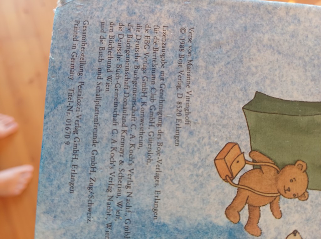 Rückseite eines Buches mit blauem Hintergrund und einem Bären, der einen Koffer hält. Darunter stehen Lizenzinformationen und der Name des Verlags.